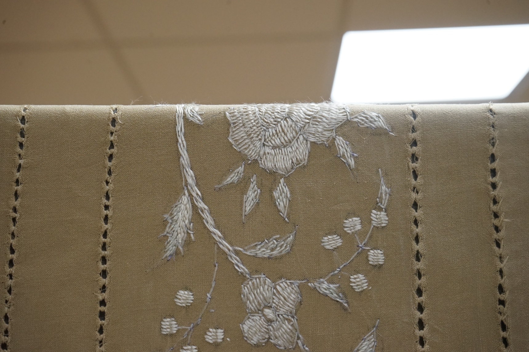 A 1920’s heavy shantung silk hand embroidered table cover. Worked with decorative rows of button hole stitch. Embroidered with white, green and blue silk flowers. 240cm x 204cm. Condition - some fine holes near corners,